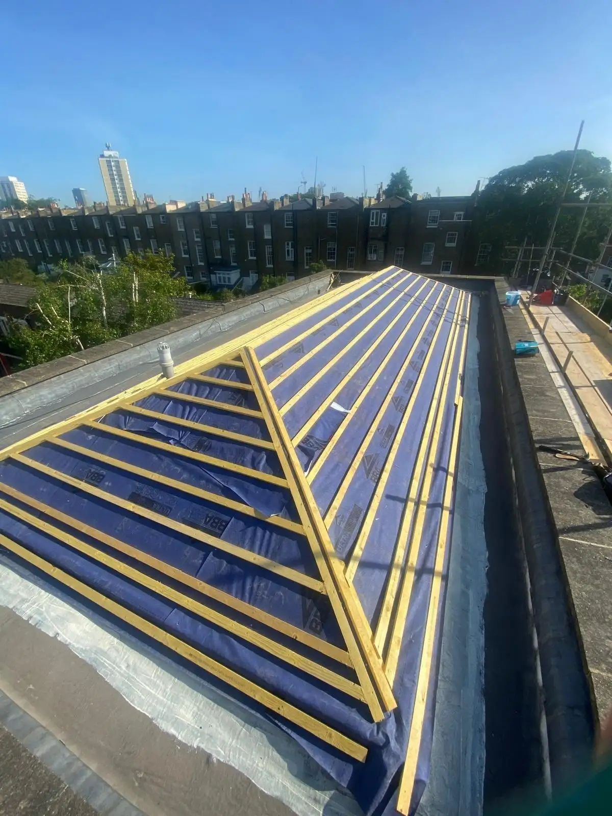 Roof in Lambeth with new blue breathable membrane and yellow timber battens set out ready for slating