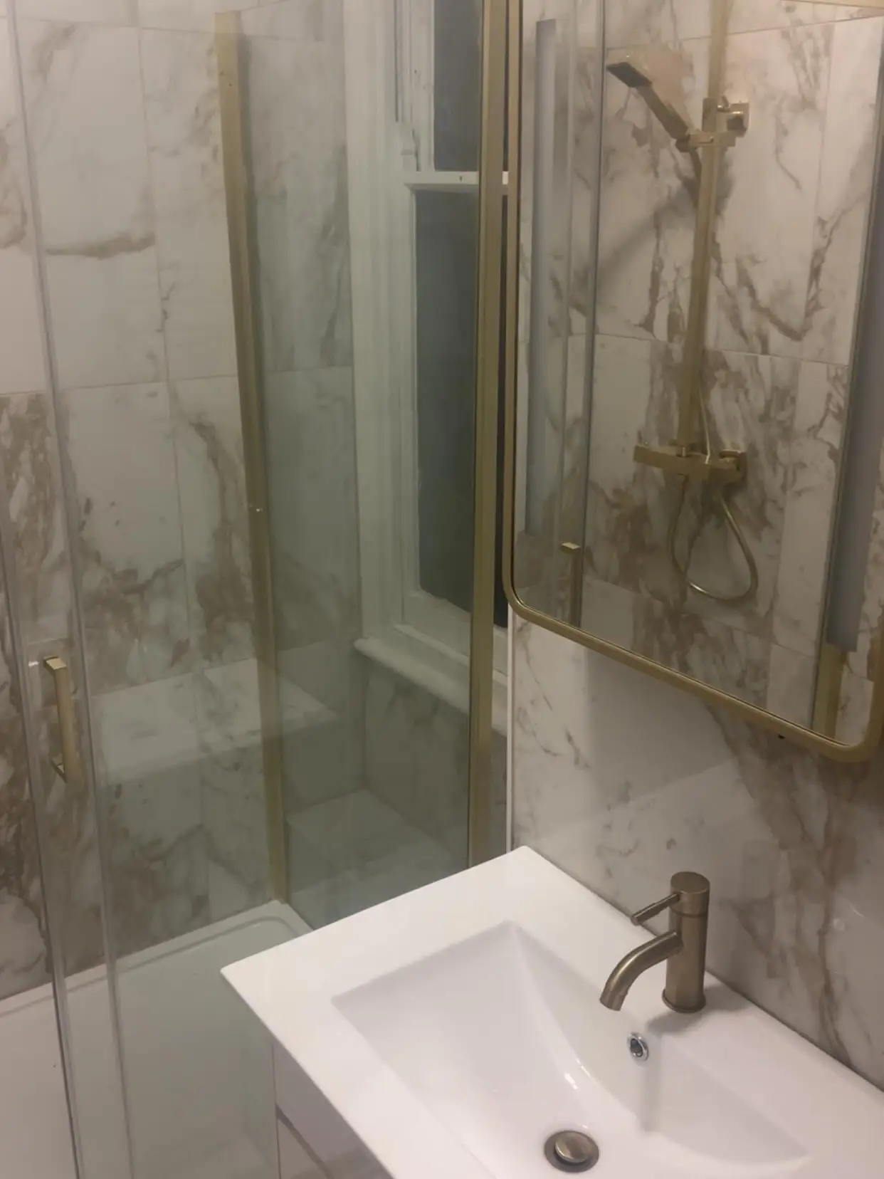 Shower with brushed gold fittings and marble-effect tiles