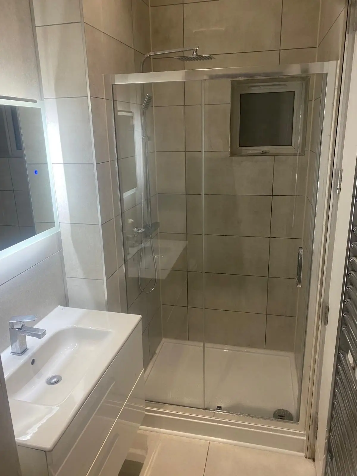 Shower enclosure with grey tiles and illuminated mirror